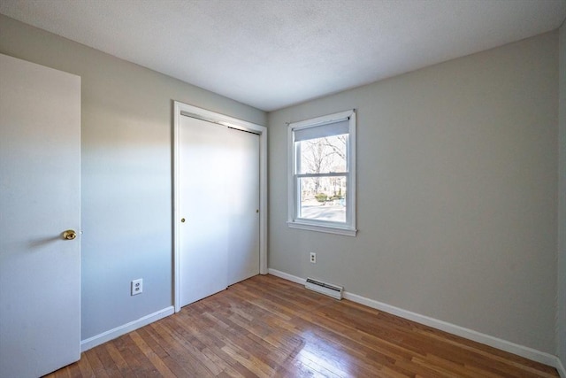 unfurnished bedroom with a closet, visible vents, baseboards, and hardwood / wood-style flooring