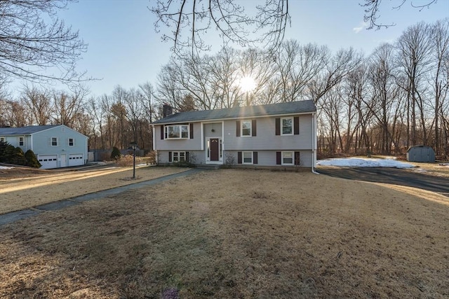 split foyer home featuring an outbuilding, a chimney, a storage shed, and driveway