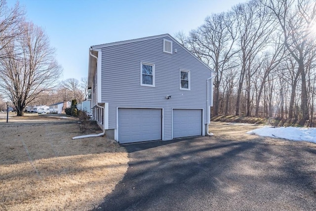 view of home's exterior with aphalt driveway and a garage