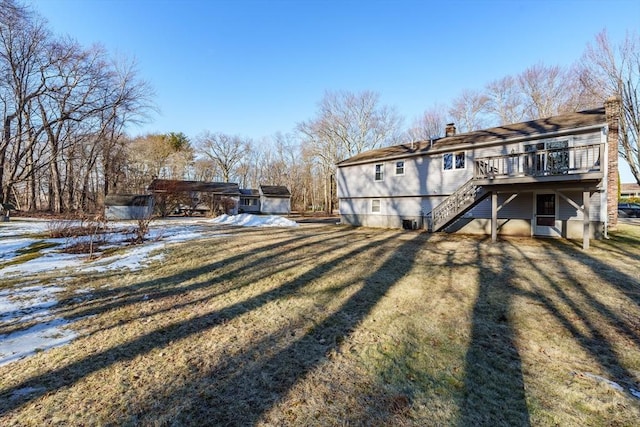 back of house featuring a chimney, stairway, a wooden deck, and a yard