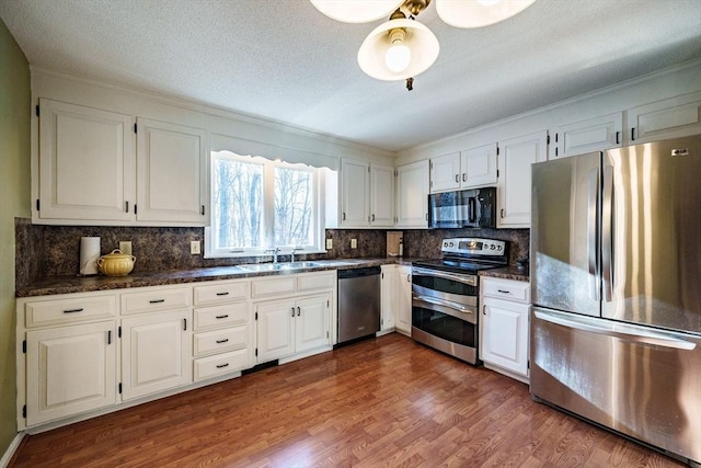 kitchen with stainless steel appliances, dark wood-style flooring, and white cabinetry