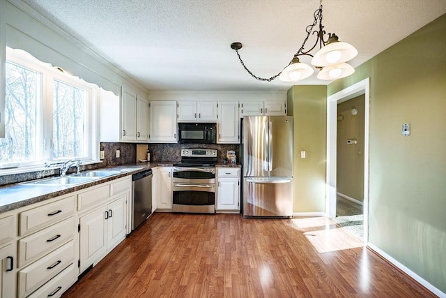 kitchen featuring white cabinetry, dark countertops, wood finished floors, and appliances with stainless steel finishes