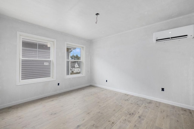 spare room featuring a wall mounted air conditioner and light hardwood / wood-style flooring