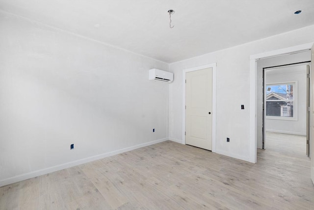 empty room featuring a wall mounted AC and light hardwood / wood-style floors