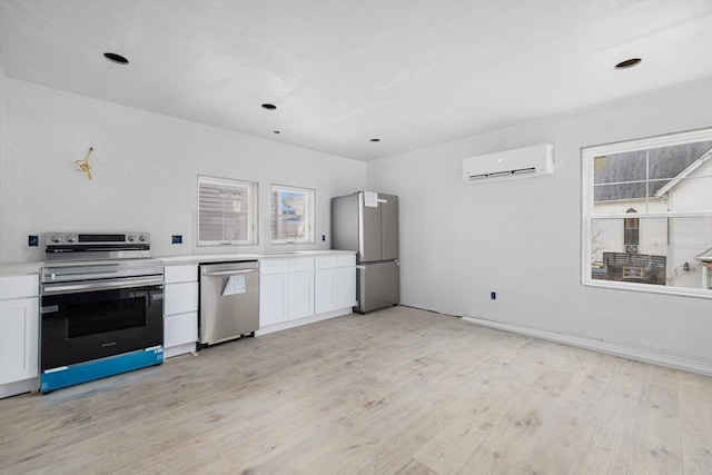 kitchen featuring stainless steel appliances, white cabinets, a wall unit AC, and light hardwood / wood-style flooring