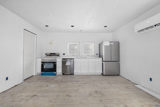 kitchen featuring stainless steel appliances, an AC wall unit, white cabinets, and light hardwood / wood-style floors