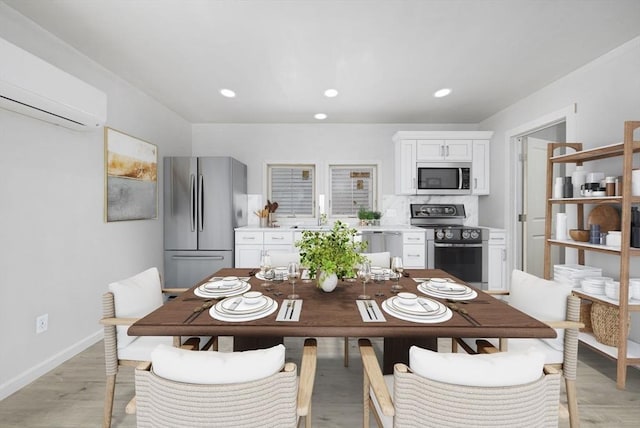 dining room featuring sink, light hardwood / wood-style flooring, and a wall mounted AC