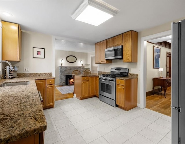 71 Dudley St, Marlborough, MA 01752 - kitchen featuring stainless steel appliances, a sink, a peninsula, stone counters, and light tile patterned floors