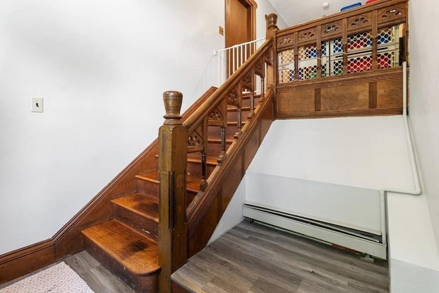 staircase with baseboard heating and wood finished floors