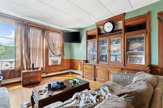 living area featuring a wainscoted wall, baseboard heating, cooling unit, and light wood finished floors