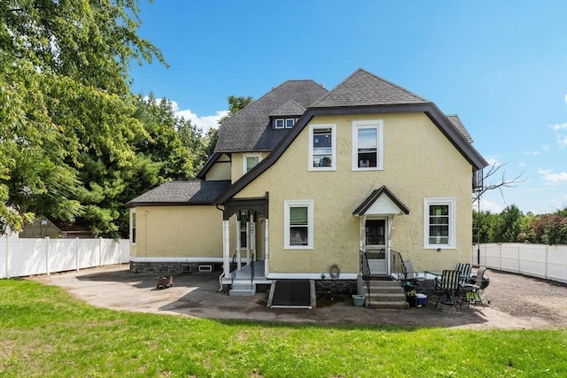 back of house with stucco siding, a patio, a lawn, and a fenced backyard