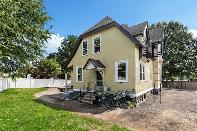 back of property with a yard, fence, roof with shingles, and stucco siding