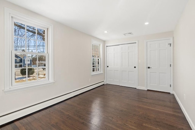 unfurnished bedroom with a baseboard radiator, multiple windows, and dark hardwood / wood-style floors