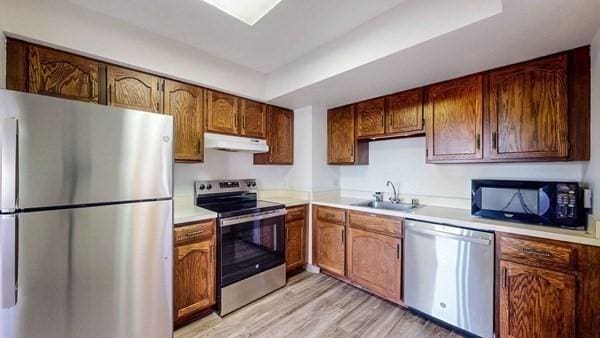 250 Hammond Pond Pkwy Unit 707S, Newton, MA 02467 - kitchen featuring stainless steel appliances, a sink, light countertops, under cabinet range hood, and light wood finished floors