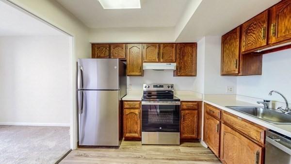 250 Hammond Pond Pkwy Unit 707S, Newton, MA 02467 - kitchen featuring appliances with stainless steel finishes, under cabinet range hood, a sink, light countertops, and brown cabinetry