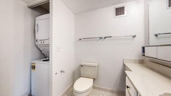 250 Hammond Pond Pkwy Unit 707S, Newton, MA 02467 - bathroom with stacked washer / drying machine, vanity, toilet, baseboards, and tile patterned floors