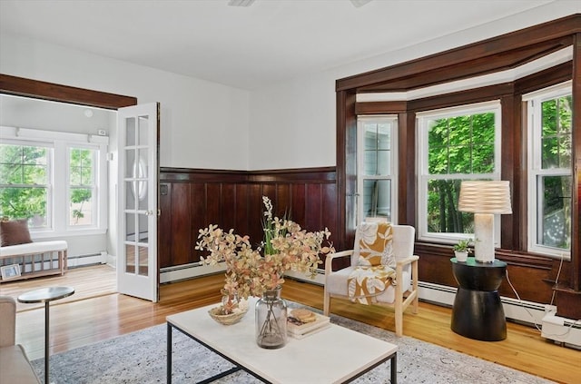 sitting room featuring healthy amount of natural light, a baseboard heating unit, baseboard heating, and wainscoting