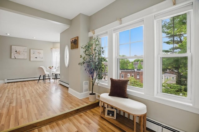 living area with baseboard heating, light wood-type flooring, baseboards, and recessed lighting