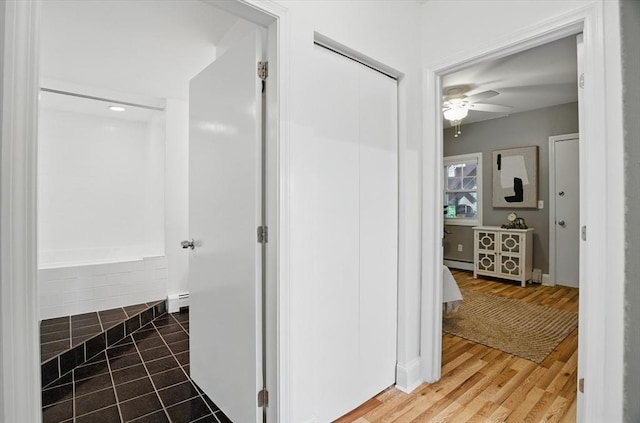 bathroom featuring baseboard heating, ceiling fan, wood finished floors, and a bathtub
