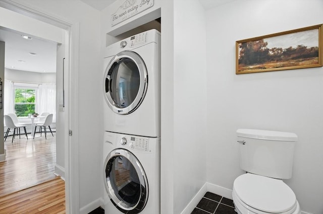 washroom with stacked washing machine and dryer and baseboards