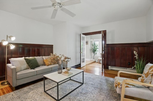 living room featuring a baseboard heating unit, wood finished floors, and ceiling fan