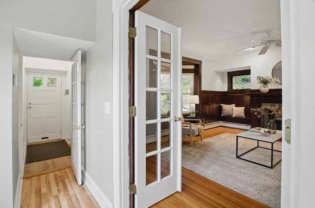interior space featuring wood finished floors, a ceiling fan, a baseboard radiator, and wainscoting