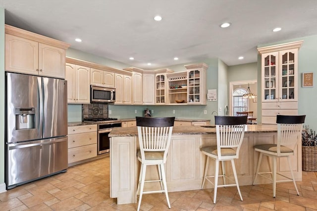 kitchen with stone finish flooring, appliances with stainless steel finishes, glass insert cabinets, and recessed lighting