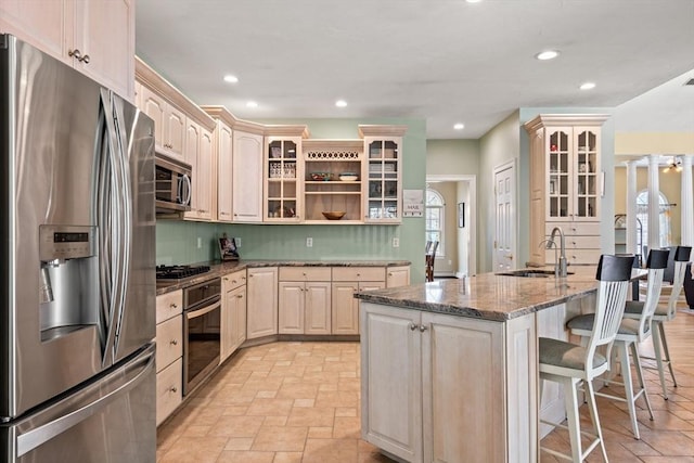kitchen featuring a kitchen bar, appliances with stainless steel finishes, open shelves, a sink, and stone tile flooring
