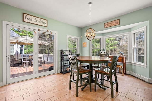 dining room featuring stone tile floors, baseboards, and an inviting chandelier