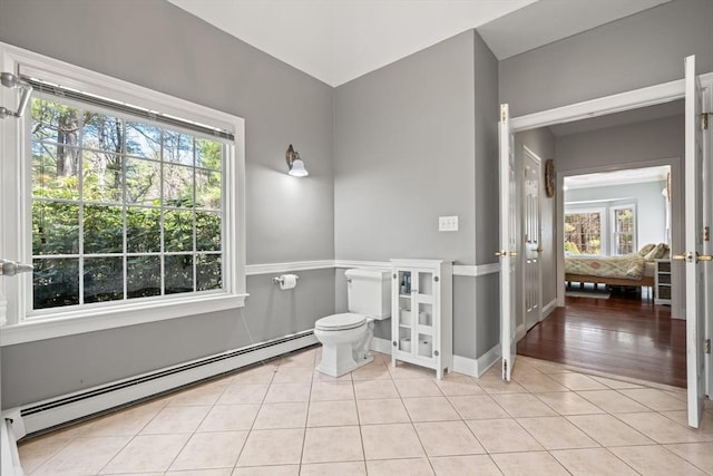 bathroom with tile patterned flooring, a baseboard heating unit, a wealth of natural light, and toilet