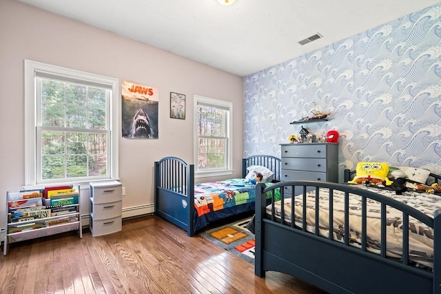 bedroom with wallpapered walls, visible vents, a baseboard radiator, and hardwood / wood-style floors
