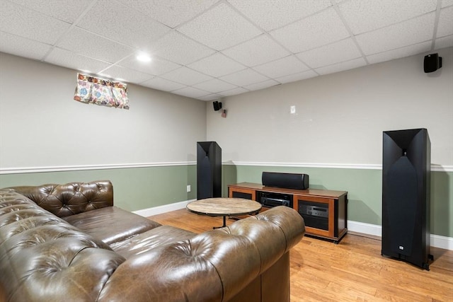 living room featuring a paneled ceiling, baseboards, and light wood-style flooring