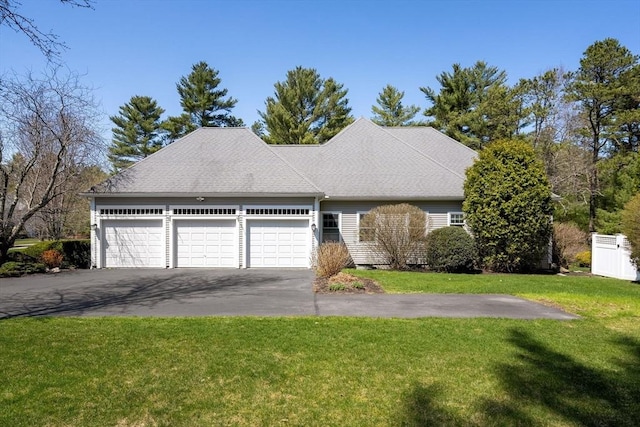 ranch-style home featuring a garage, a front lawn, driveway, and a shingled roof
