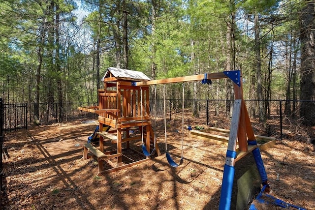 view of jungle gym with fence and a wooded view