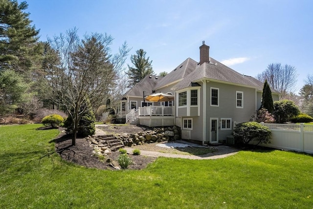 back of property with fence, a deck, a chimney, a yard, and stairway