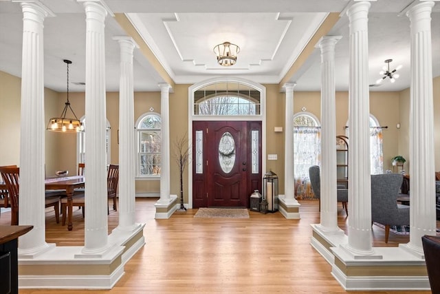 foyer with baseboards, a tray ceiling, light wood-style flooring, and a notable chandelier