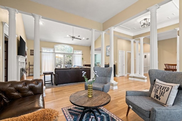 living area featuring light wood-style floors, crown molding, decorative columns, and ceiling fan