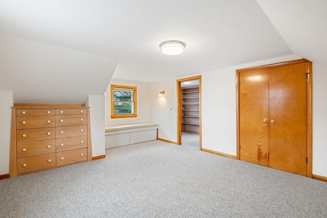 additional living space featuring baseboards, lofted ceiling, and carpet flooring