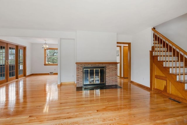 unfurnished living room with wood finished floors, baseboards, visible vents, and a notable chandelier