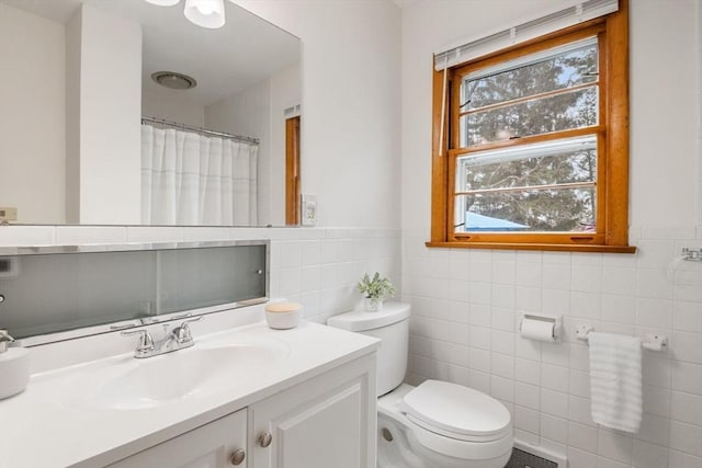bathroom with vanity, toilet, curtained shower, and tile walls