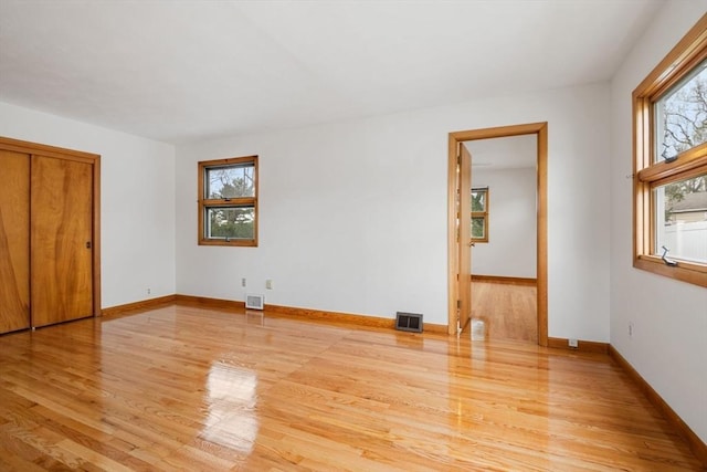 unfurnished bedroom featuring light wood finished floors, multiple windows, and visible vents