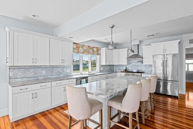 55 Seaside Rd, Scituate, MA 02066 - kitchen with stainless steel appliances, wall chimney exhaust hood, white cabinetry, wood finished floors, and recessed lighting