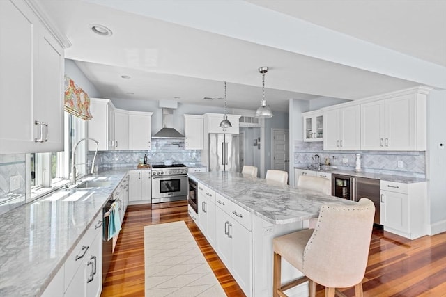 55 Seaside Rd, Scituate, MA 02066 - kitchen with high quality appliances, wall chimney exhaust hood, a sink, dark wood finished floors, and recessed lighting