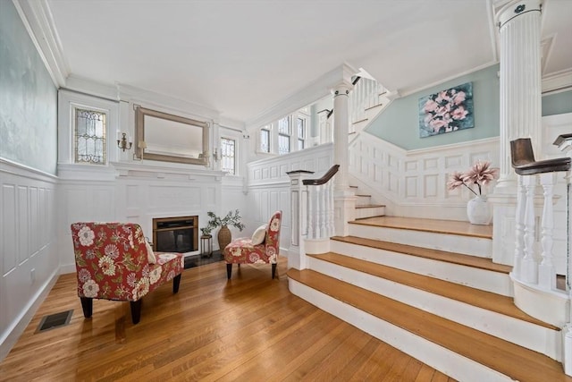 sitting room featuring visible vents, stairway, wood finished floors, and ornamental molding