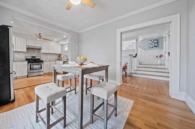 dining room featuring ornamental molding, a ceiling fan, recessed lighting, light wood-style floors, and stairs