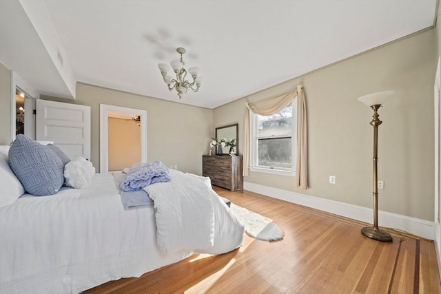 bedroom featuring visible vents, baseboards, an inviting chandelier, and wood finished floors