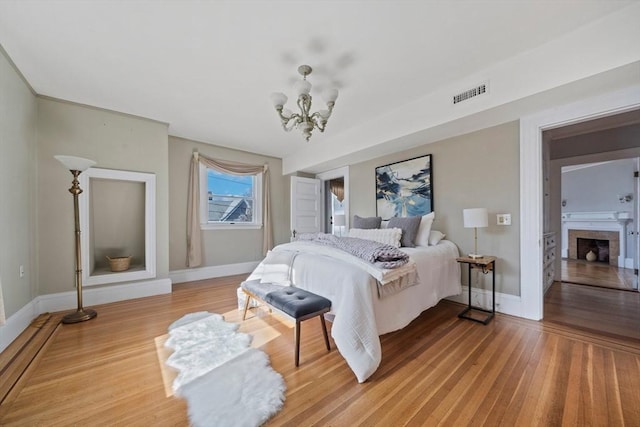 bedroom with visible vents, baseboards, light wood-style floors, and a fireplace