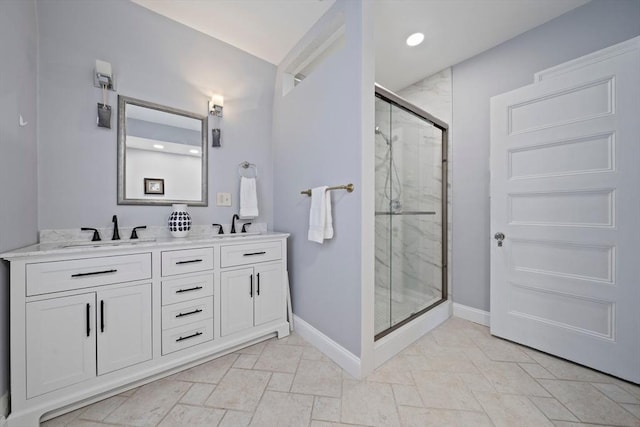 bathroom featuring a sink, a marble finish shower, baseboards, and double vanity