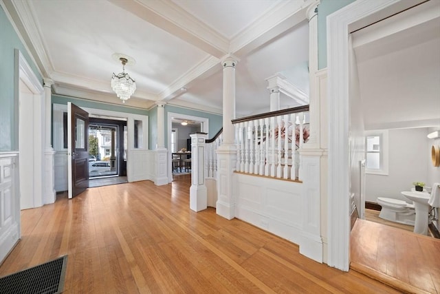 entryway with visible vents, light wood finished floors, ornamental molding, stairs, and a decorative wall