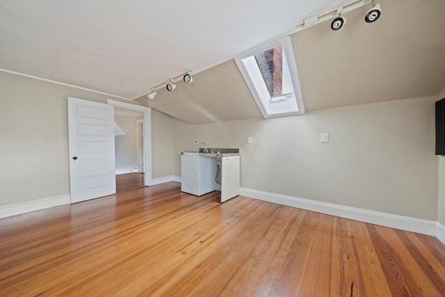 bonus room featuring lofted ceiling with skylight, light wood-type flooring, baseboards, and a sink